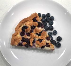 sbriciolata con ricotta e mirtilli in piatto bianco