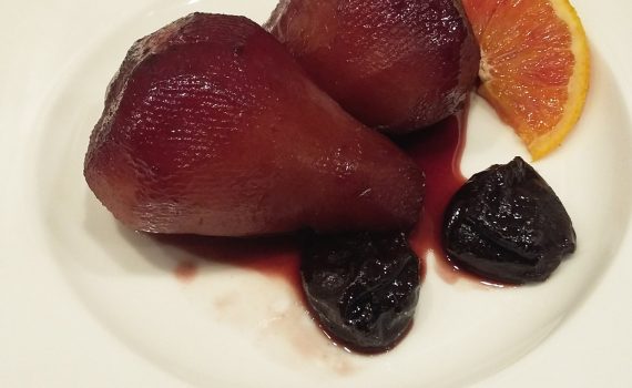 pere al vino servite con prugne e fetta di arancia